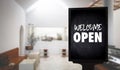 Come in WeÃ¢â¬â¢re OpenÃ¢â¬â¢ on cafe waiter standing in front of coffee shop vintage retro sign Royalty Free Stock Photo